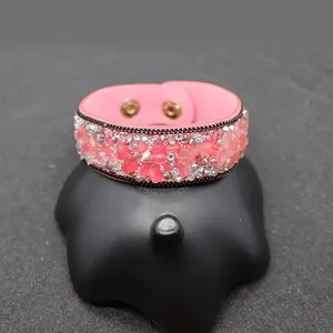 Detail of pink leather bracelet with crushed stones, rhinestones and golden snap buttons