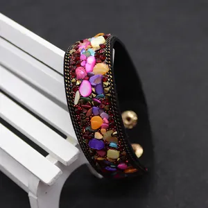 Detail of colorful stone chips on black leather bohemian bracelet with golden clasp