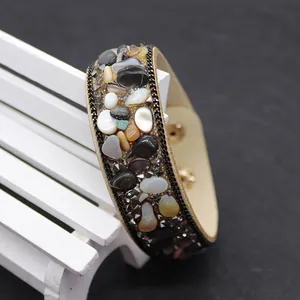 Detailed close-up of wide leather bracelet with natural stones and metal chain trim