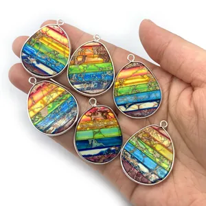 Rainbow emperor stone teardrop pendants with silver plating held in hand for size