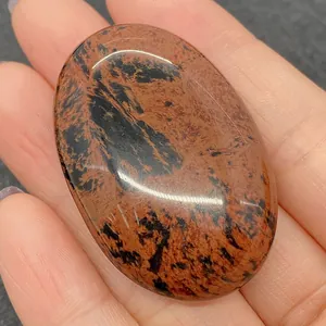 Close-up of a polished oval Mahogany Obsidian gemstone with red and black patterns