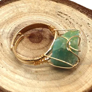 Detalle macro de un anillo artesanal de hilo dorado con piedra aventurina verde