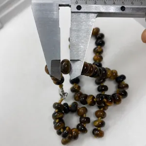 Vista ravvicinata di perle occhio di tigre da 8,5 mm misurate con un calibro in metallo
