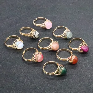 Macro detail of nine handmade beaded rings with colorful natural stones and gold wire wrap