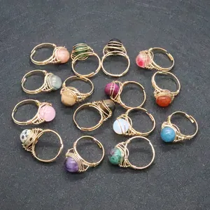 Flat lay of thirteen handmade gold wire-wrapped rings with various natural stone beads
