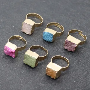 Vista dall'alto di anelli con pietre druzy quadrate multicolori e fascia dorata
