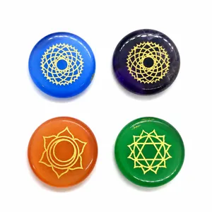 Close-up of polished chakra energy stones with golden geometric symbols on white background