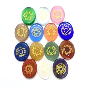 Close-up of oval chakra stones with golden engraved symbols on a clean white surface