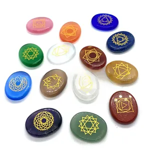 Polished chakra energy stones set with engraved gold symbols on a white background
