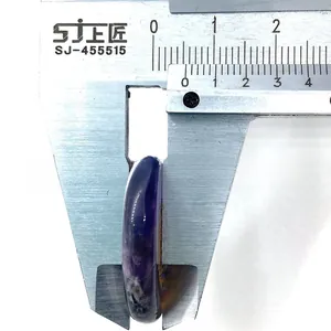 Macro shot measuring the 8mm thickness of a purple oval gemstone with a metal caliper