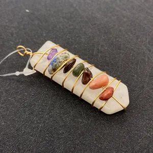 Détail macro d'un pendentif en cristal blanc avec fils dorés et pierres de chakra colorées