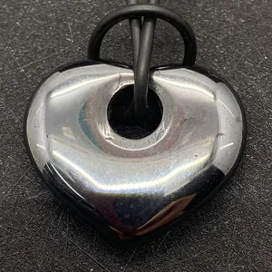 Macro-opname van een metalen hartvormige hematiet hanger aan een zwart rubberen koord