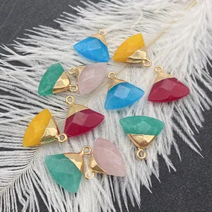 Macro view of multi-color faceted stone pendants with gold metal loops on white feathers