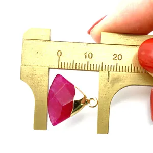 Macro view of pink stone pendant measured with a caliper showing 15mm width