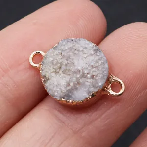 Macro shot of white crystal druzy connector with gold plating held between fingers