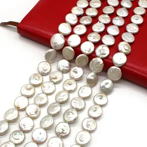 Natürliche weiße Süßwasser-Münzperlen auf einem roten Notizbuch für DIY-Schmuck