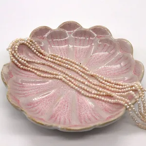Makroaufnahme von Natur-Süßwasserperlen auf einer muschelförmigen rosa Keramikplatte