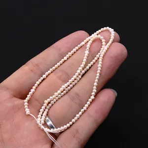 Detailansicht natürlicher 2-3mm rosa Süßwasserperlen für DIY-Schmuck in der Hand gehalten