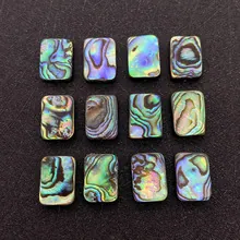 Dettaglio di dodici ciondoli rettangolari in conchiglia di abalone con riflessi arcobaleno