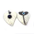 Detailsicht auf herzförmige Muschelanhänger mit Evil Eye und Edelstein-Inlays
