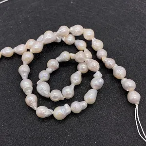Gros plan de perles d'eau douce baroques naturelles aux reflets blanc-rose sur fond noir