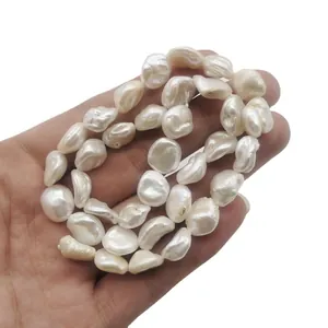 Main tenant des brins de perles d'eau douce baroques naturelles blanches lustrées