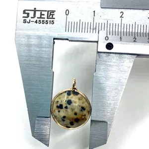 Macro shot measuring a 14mm round dalmatian jasper stone pendant with gold bezel