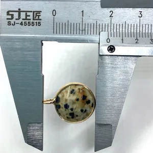 Measuring a round dalmatian jasper pendant with gold rim using a digital caliper