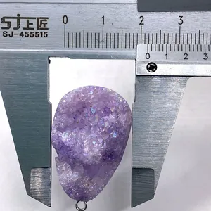 Macro-opname van amethist druzy hanger in schedelvorm gemeten met een schuifmaat