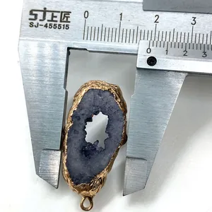 Macro shot measuring a purple druzy stone pendant with golden electroplated edges