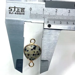 Macro shot of a heart-shaped dalmatian stone connector measuring 15mm with gold loops