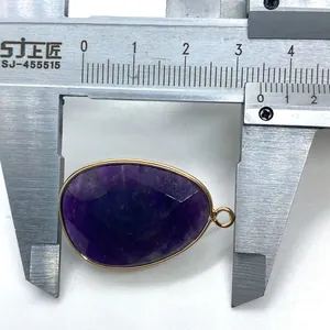 Macro detail of purple faceted gemstone pendant being measured with a metal caliper