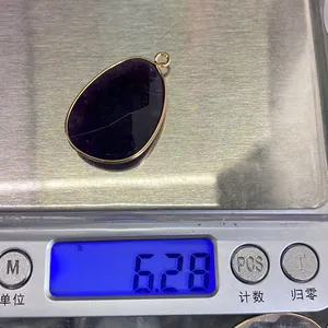 Macro view of teardrop amethyst pendant with gold edging on a digital scale weighing 6.28g