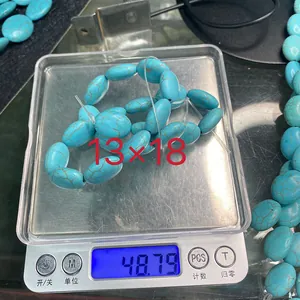 Makroaufnahme von 13x18 mm ovalen synthetischen Türkisperlen auf einer Waage für Gewicht