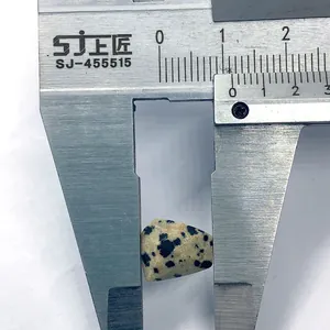 Dettaglio macro di perla in diaspro dalmata che mostra la misura 13mm con calibro in metallo