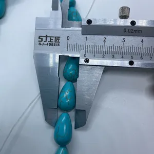 Vue macro de la mesure d'une perle turquoise en goutte avec un pied à coulisse en métal