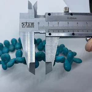 Close-up of a blue-green teardrop turquoise bead measured by a caliper showing 10mm width