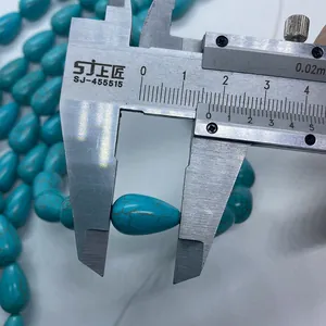 Gros plan d'une perle turquoise en forme de goutte de 15mm mesurée au pied à coulisse
