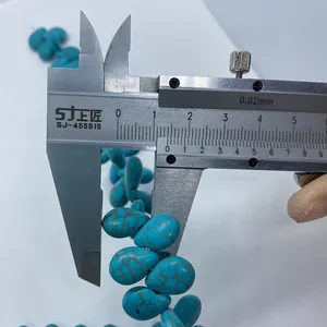 Macro shot showing 15mm turquoise teardrop beads measured with a metal caliper
