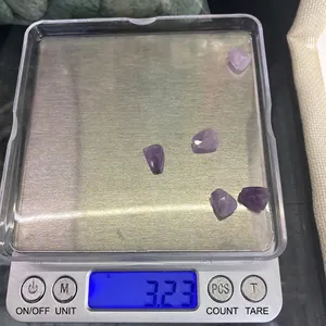 Dettaglio macro di 5 pietre di ametista viola sfaccettate che pesano 3,23g su bilancia