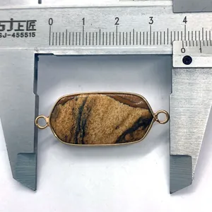 Macro detail of oval jasper pendant with gold trim showing 44mm measurement on a caliper