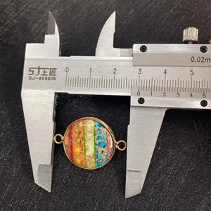 Macro view of 25mm round rainbow stone connector with gold rim being measured by caliper