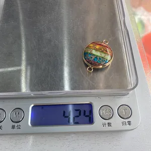 Macro view of a circular natural stone connector with gold frame weighing 4.24g on a scale
