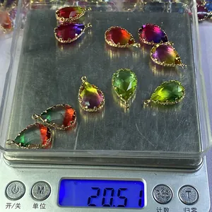 Macro di nove cristalli sfaccettati a goccia con castoni dorati pesati su bilancia digitale