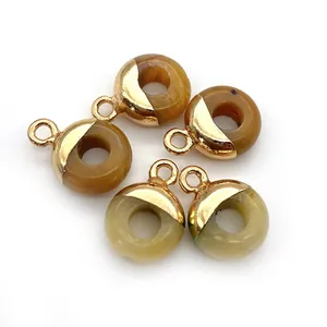 Detail van donutvormige hangers van natuursteen met vergulde ophanglussen