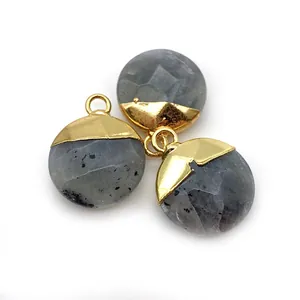 Macro shot of three faceted natural gray stones with gold-plated caps and hanging loops