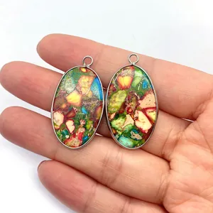 Vue à la main de pendentifs ovales en pierre naturelle multicolore avec cadre en argent