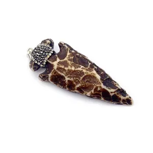 Pendentif flèche en résine avec motifs bruns et strass scintillants sur fond blanc