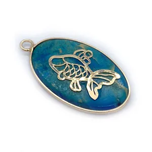 Detail of oval blue stone pendant with golden fish inlay and metallic frame design