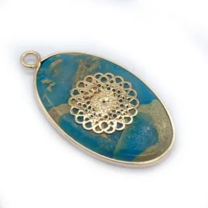 Detail of blue natural stone oval pendant with golden filigree mandala inlay and metallic rim